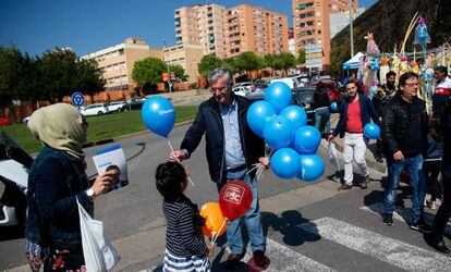 Un hombre entrega a una niña un globo con el logo del PP en una calle de Barcelona.