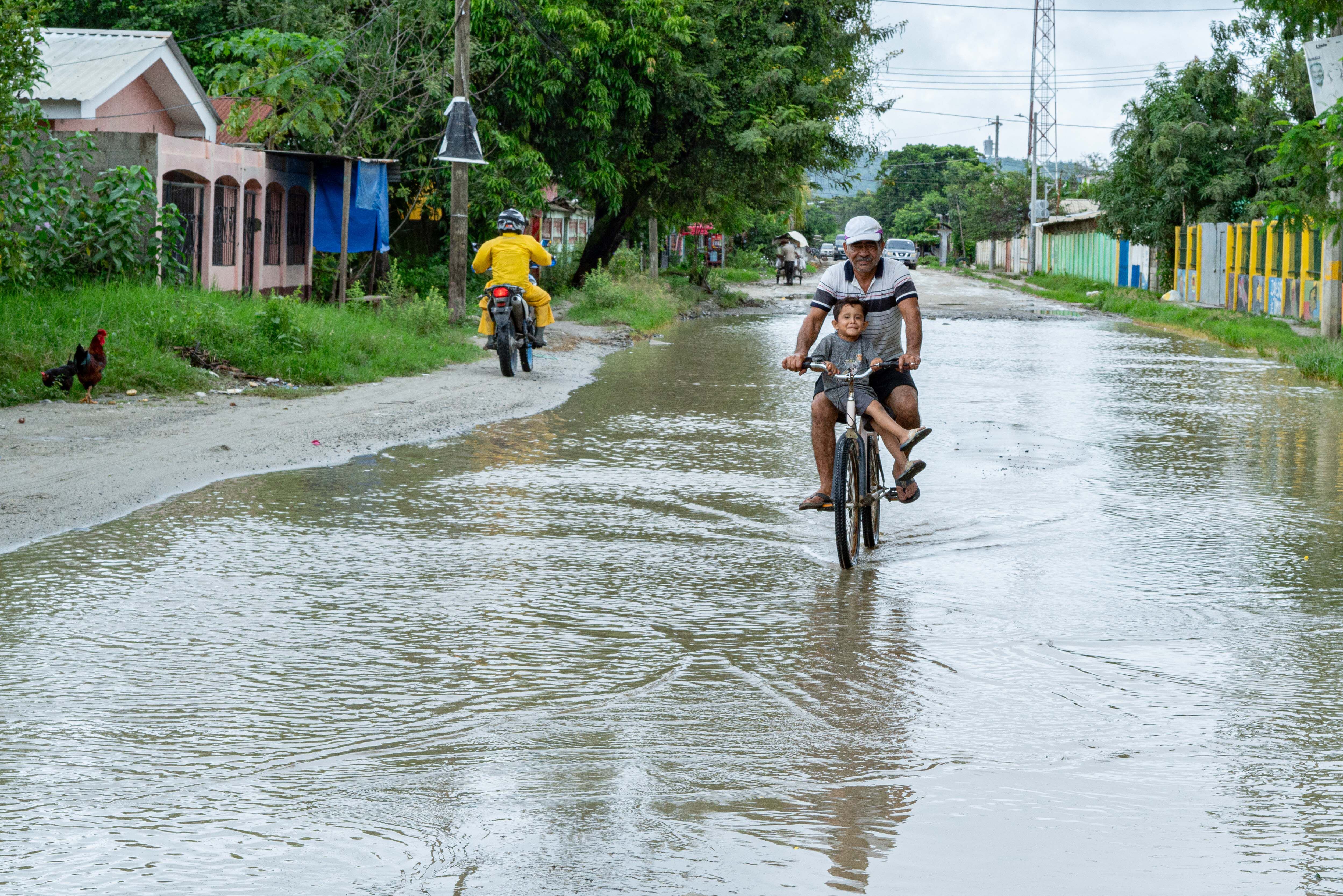 Un hombre y su nieto recorren las calles inundadas de la comunidad La Lacayo, en el Sector Rivera Hernández.