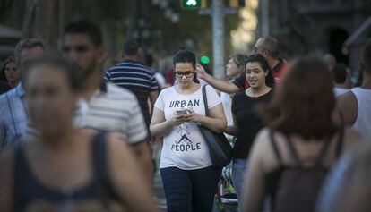 Una joven pasea con la mirada fija en la pantalla.