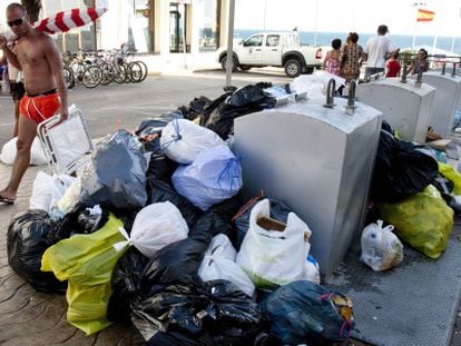 Un veraneante pasa por un calle de Rota donde se acumula basura.