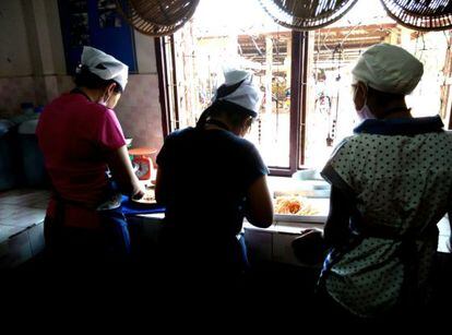 Tres menores que fueron víctimas de trata cocinan en el albergue de la ONG Focus Village International en Pakse (Laos).