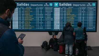 Pasajeros revisan el tablero de salidas en el Aeropuerto Internacional Benito Juárez (MEX) en la Ciudad de México, México, en 2022.