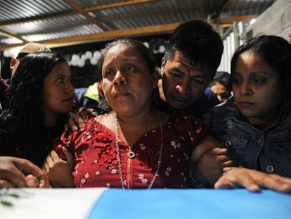 Familiares del difunto migrante Francisco Rojche Chiquival, quien murió durante un incendio en un centro de detención de migrantes en la ciudad fronteriza mexicana de Ciudad Juárez, junto a su ataúd durante un velorio en Nahualá (Guatemala), el 12 de abril de 2023.