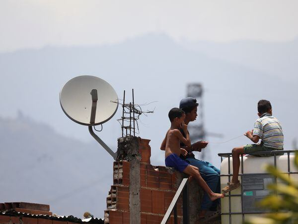 Children play near a satellite tv antenna in the low-income neighbourhood Catia after AT&T Inc said on Tuesday it has closed its DirecTV Latin America operations in Venezuela, in Caracas, Venezuela May 19, 2020. REUTERS/Manaure Quintero