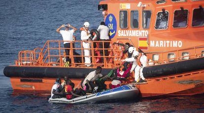 Trabajadores de Salvamento Marítimo ayudan a embarcar a 11 migrantes que cruzaban en un bote de plástico a remos el Estrecho.