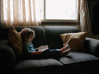 Una niña lee en el sillón. 