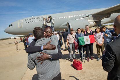 Uno de los civiles evacuados por España de Sudán se abraza mientras un grupo de mexicanos se hace una foto a su llegada a Torrejón.