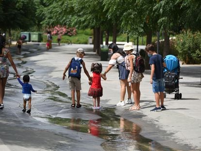 Varios niños, acompañados por adultos, pasean por un arroyo en Valencia el pasado jueves.