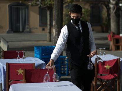 Un camarero prepara las mesas de una terraza para el turno de las comidas.