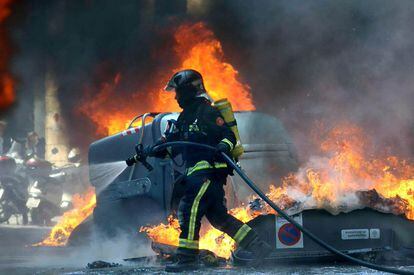 Un bombero intenta apagar los contenedores incendiados en la calle Balmes de Barcelona.