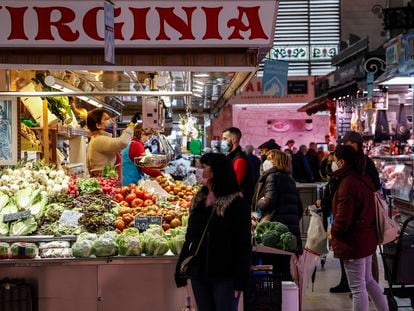 Varias personas compran en un puesto de fruta y verdura en un mercado de Valencia.