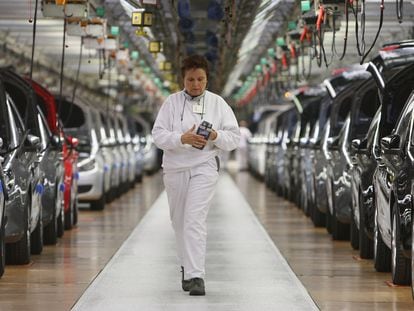 Una trabajadora del grupo VW camina entre dos filas de Volkswagen Golf en la factoría de Wolfswurgo (Alemania).