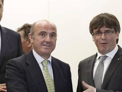 El presidente de la Generalitat, Carles Puigdemont saluda al ministro de Econom&iacute;a, Industria y Competitividad del Gobierno, Luis de Guindos, en presencia del presidente del PPC, Xavier Garcia Albiol.