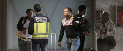 Un policía con viajeros llegados al aeropuerto de Barajas.
