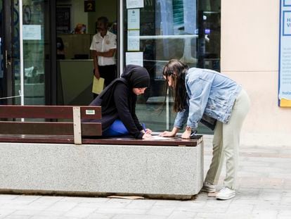 Dos mujeres rellenan un impreso delante de la única oficina de Correos de Melilla, el jueves.