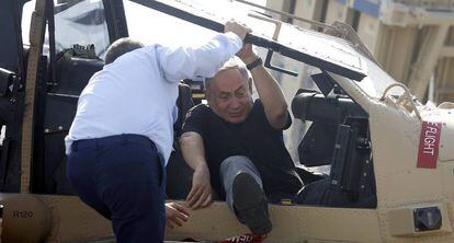 El primer ministro israelí, Benjamin Netanyahu, sale de un helicóptero ayudado por el comandante de la fuerza aérea de Israel.