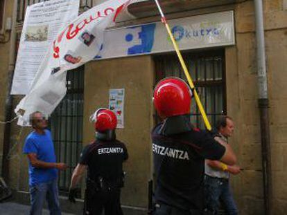Agentes de la Ertzaintza retiran ayer una pancarta en San Sebastián.