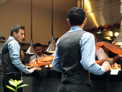 Dos camareros esperan en la barra de Central Restaurante a que salgan los platos.