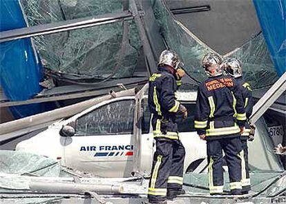 Tres bomberos inspeccionan el muelle de embarque desplomado en el aeropuerto parisiense Charles de Gaulle.