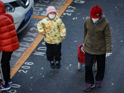 Un niño y una mujer con mascarillas a la salida de un colegio en Pekín, este jueves.