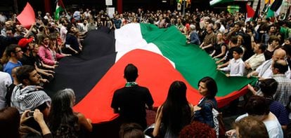 Manifestantes portan una gran bandera palestina en la protesta en  frente a la Cámara de Comercio israelí en Barcelona.