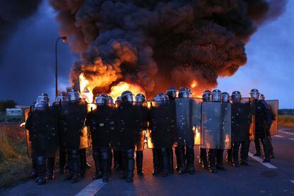 Agentes antidisturbios franceses avanzan delante de una barricada en llamas para proceder al desalojo de los manifestantes que bloquean la entrada a una refinería en Douchy-les-Mines, al noreste de Francia.