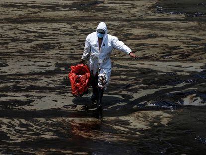 Un trabajador camina en la playa peruana de Ventanilla tras un derrame de petróleo causado por olas anormales, provocadas por la erupción del volcán Hunga Tonga-Hunga Ha'apai.