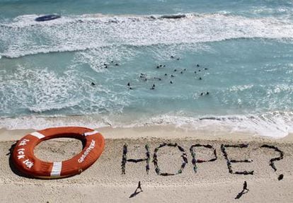 Activistas de Greenpeace demandan "esperanza" para luchar contra el cambio climático en la playa de Cancún.