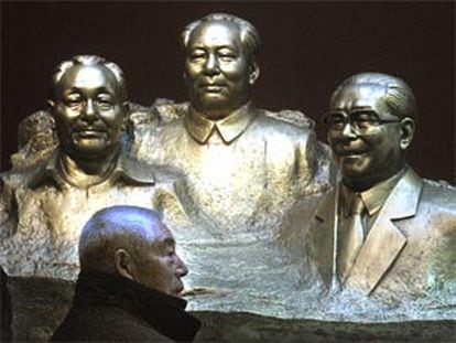 Un chino pasa junto a un grupo escultórico que representa a Deng Xiao Ping, Mao Zedong y Jian Zeming.