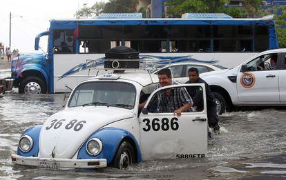 Los residentes empujan un taxi por una calle inundada en Acapulco. Como consecuencia del alto oleaje y las inundaciones al menos 218 viviendas del estado de Guerrero resultaron dañadas, mientras que 165 personas permanecen en los tres albergues que fueron habilitados por la Secretaría de Protección Civil.