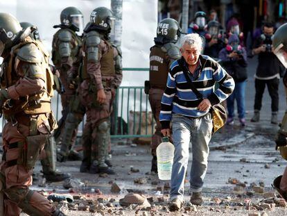 Un hombre camina entre policías antimotines durante las protestas registradas en Santiago el 18 de noviembre pasado.