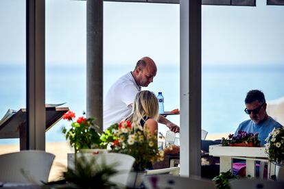 A waiter attends to a couple on the terrace of a restaurant in Playa de Aro (Costa Brava-Girona).