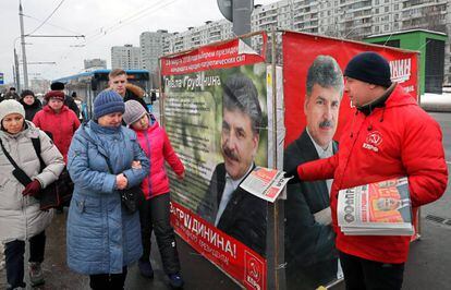 Un miembro del partido comunista reparte panfletos junto a carteles de la campaña electoral del candidato comunista el13 de marzo de 2018.