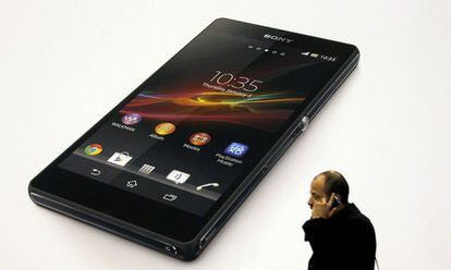 Un visitante utiliza su teléfono móvil ante un anuncio del nuevo Sony Xperia Z.