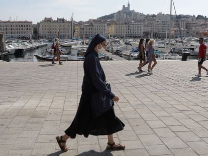 Una monja camina con mascarilla por el viejo puerto de Marsella