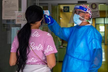 Un sanitario le mide la temperatura a una mujer en la entrada del centro de salud Puerta Bonita en Carabanchel, Madrid.