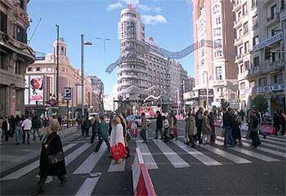 Decenas de peatones cruzan la Gran Vía, a la altura de la plaza del Callao, en el último domingo navideño de cortes de tráfico.