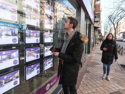 Un joven observa la oferta de pisos de una inmobiliaria en Madrid.