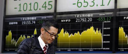 Un peatón pasa delante de unos paneles con las cotizaciones del índice de la Bolsa japonesa, el Nikkei 225.