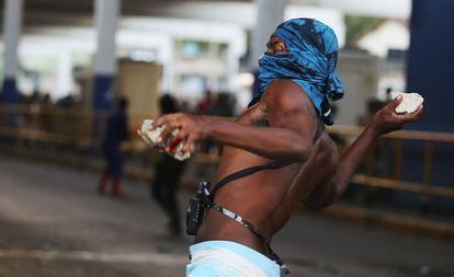 Un manifestante lanza piedras a la policía fuera de la estación central de trenes, durante protesta contra el aumento en las tarifas de autobús en Río de Janeiro, Brasil.