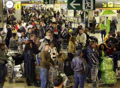 Cientos de pasajeros hacen cola ayer para facturar sus equipajes en la terminal T-1 del aeropuerto de Barajas.