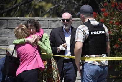 Dos mujeres se abrazan en el exterior de la sinagoga Chabad, en Poway, California.