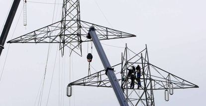 Varios operarios reparan una torre de tendido eléctrico.