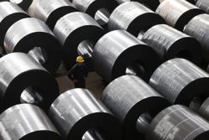 Unm operario chino pasea entre bobinas de acero en una sider&uacute;rgica en la provicncia de Zhejiang.