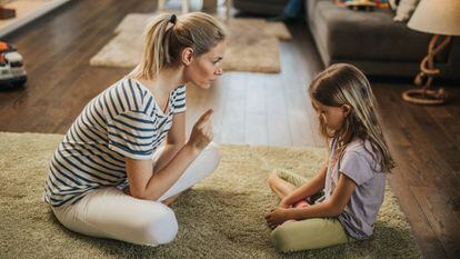 Una madre habla con su hija en el salón. 