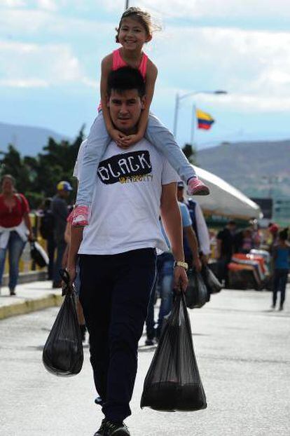 Un padre carga con su hija en el puente Sim&oacute;n Bol&iacute;var, frontera entre Colombia y Venezuela, el pasado domingo.