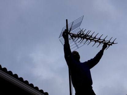 Un home recol&middot;locant una antena de TDT