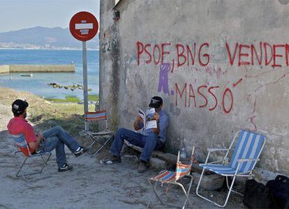 Dos vecinos contrarios al puerto deportivo de Cangas vigilan la entrada junto a la señal de la discordia