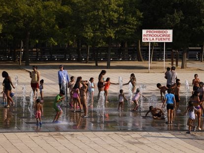 Unos niños se refrescan en las fuentes del parque de Juan Carlos I de Madrid, el lunes en plena ola de calor.