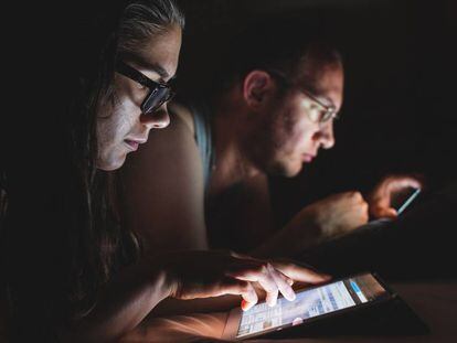 Una pareja lee en sus dispositivos móviles.